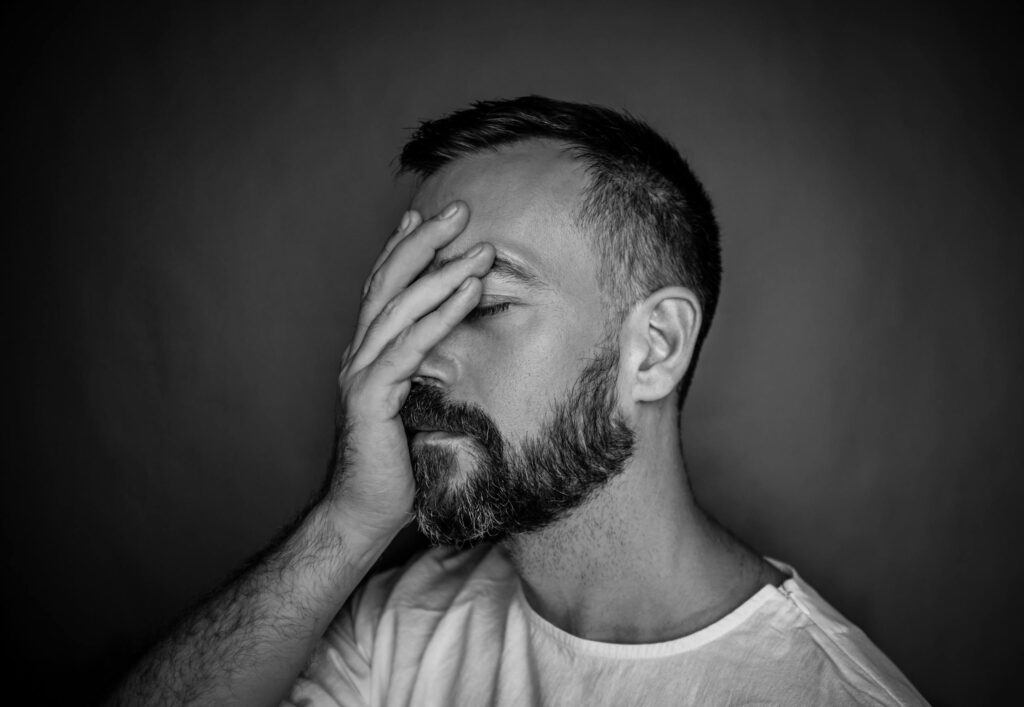 Expressive black and white portrait of a bearded man showing stress and contemplation.